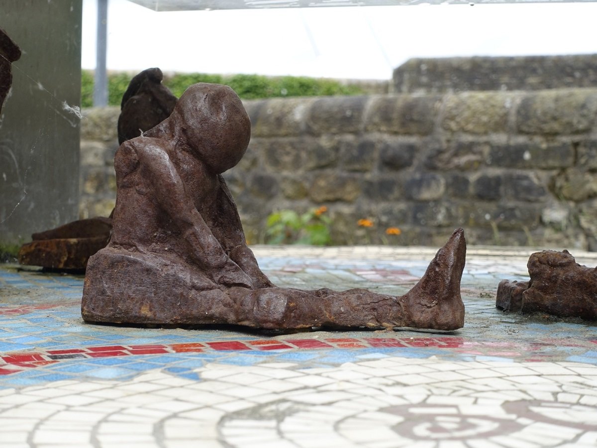 Statue of a man sitting on the ground with hanging head