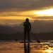 Person on a paddleboard on the water, against a yellow cloudy sky